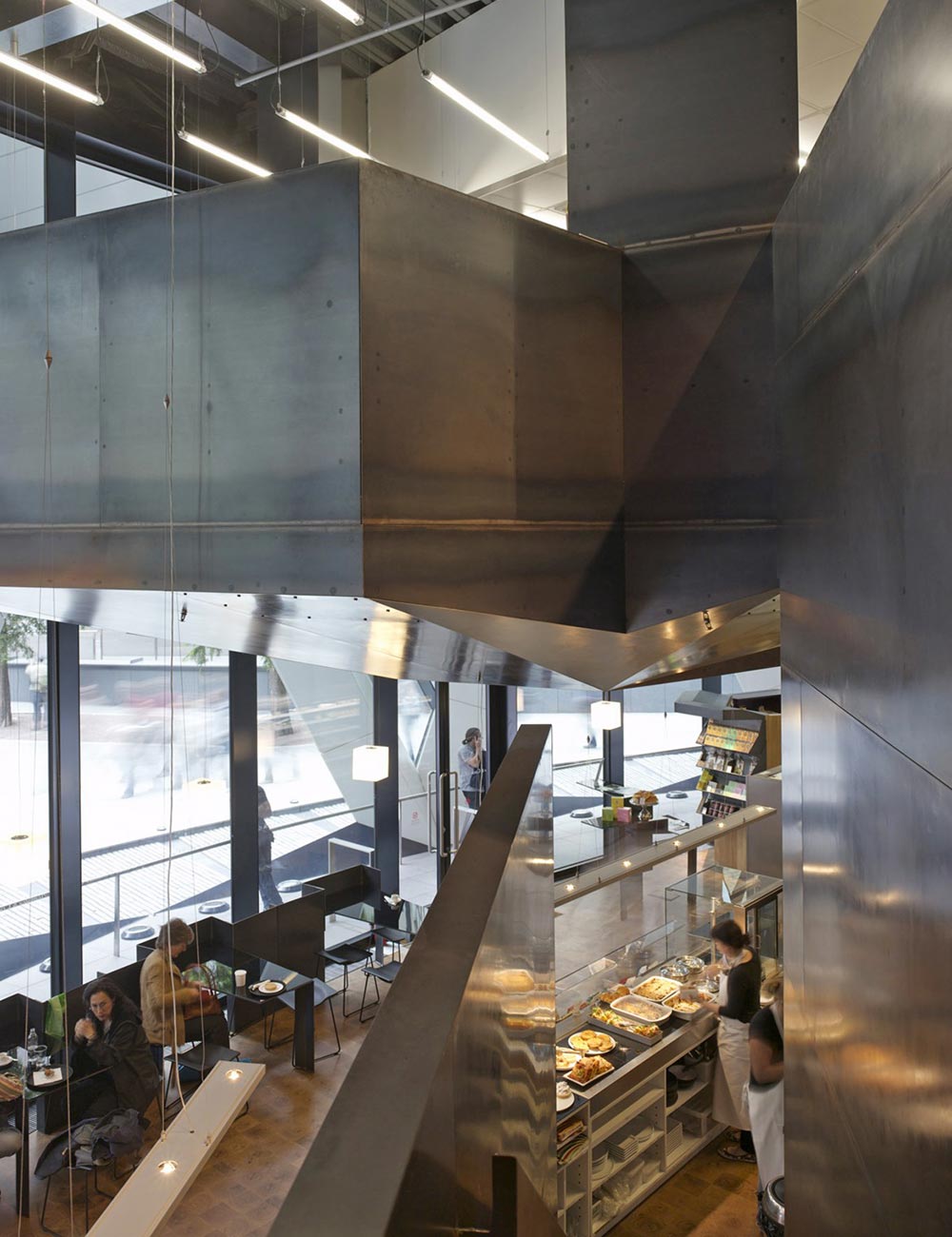 A shop, café and specialist kitchen are accommodated within the double-height ground floor space behind the entrance to 30 St Mary Axe. A new commercial kitchen level is suspended from the ceiling creating a striking, sculpted steel ceiling to the café level below. Both the mezzanine and stair are fabricated from 3mm steel panels. Steel is also used for furniture, while warmth is added by an end-grain oak floor and distinctive glass panels, back painted in a rich purple hue that allows the seamless integration of the client’s established brand. We provided all mechanical and electrical services.